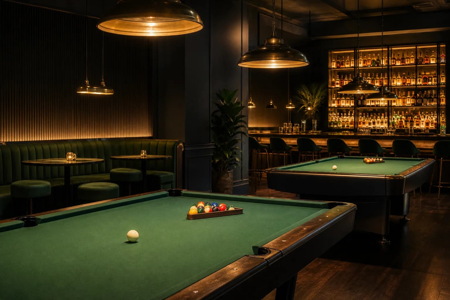 A moody pool lounge with brass lights over green felt tables